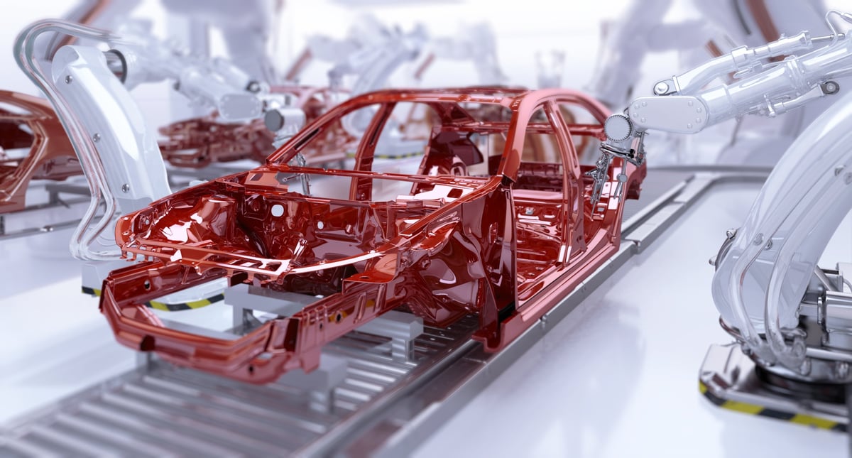 Automated car manufacturing. Industrial robotic arms painting vehicle body on a production line.